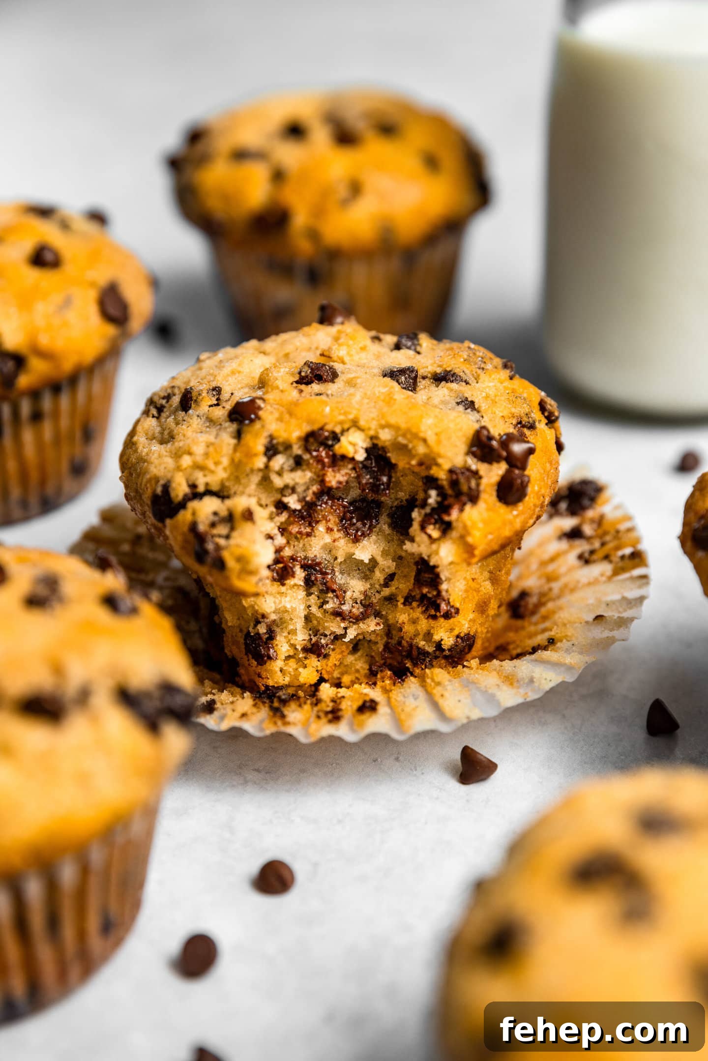 Close up of Small Batch Chocolate Chip Muffin with a bite taken out of it next to a glass of milk