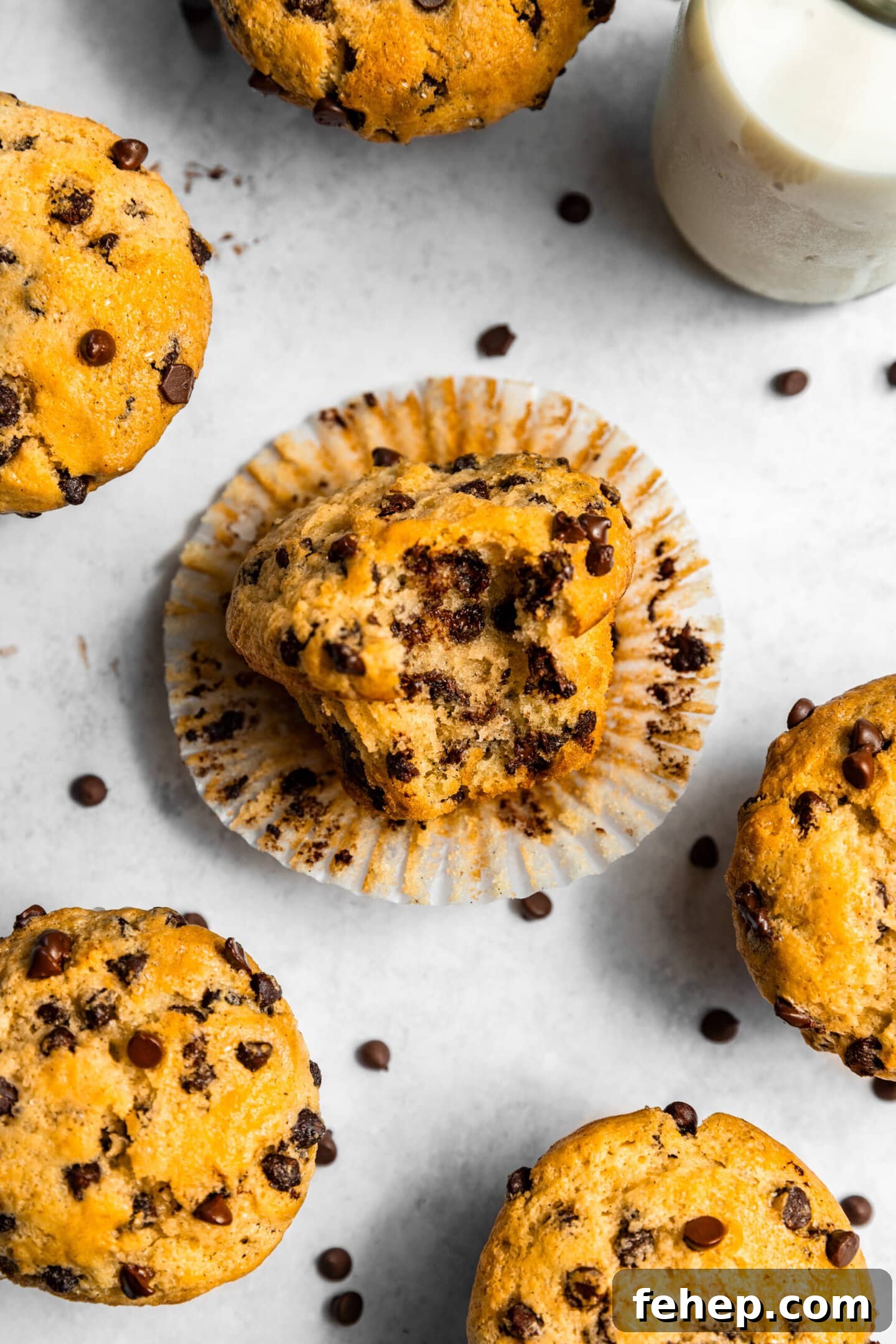 Close up of chocolate chip muffin on its side with a bite missing showing melted chocolate chips inside.