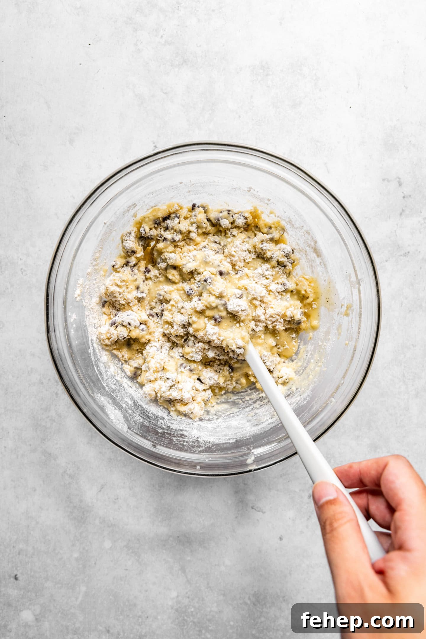 Dry ingredients and chocolate chips being folded into muffin batter.