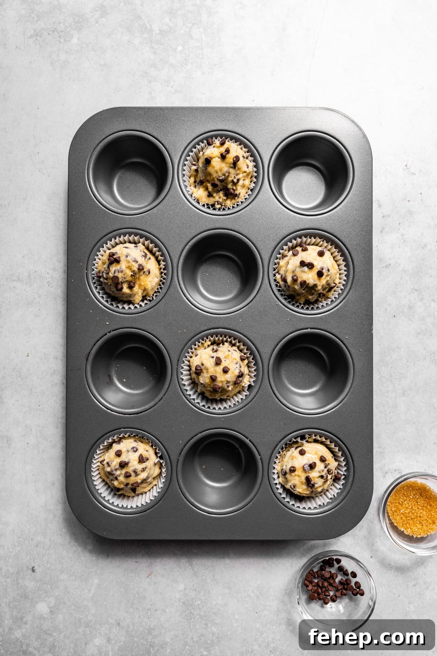 Muffin batter scooped into muffin pan with raw sugar sprinkled on top