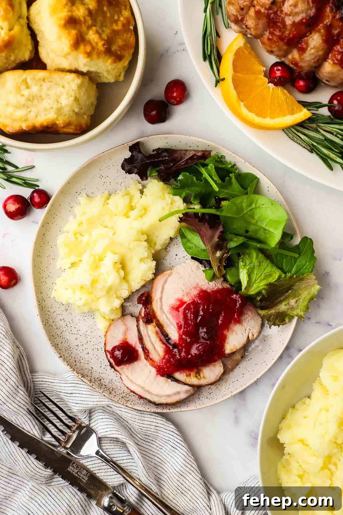 cranberry glazed pork loin roast served on a plate with some mashed potatoes and greens