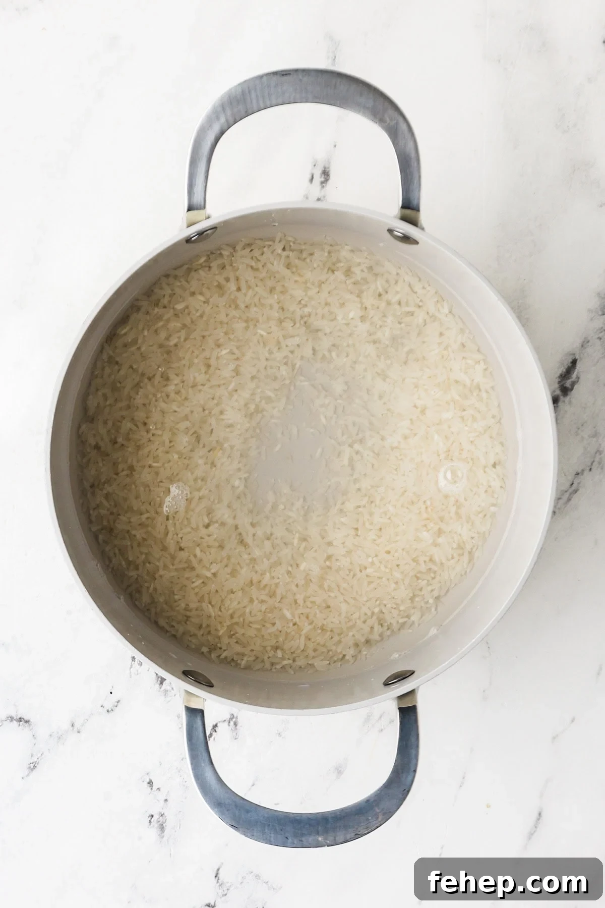 An overhead image of cooking rice with water in a saucepan.