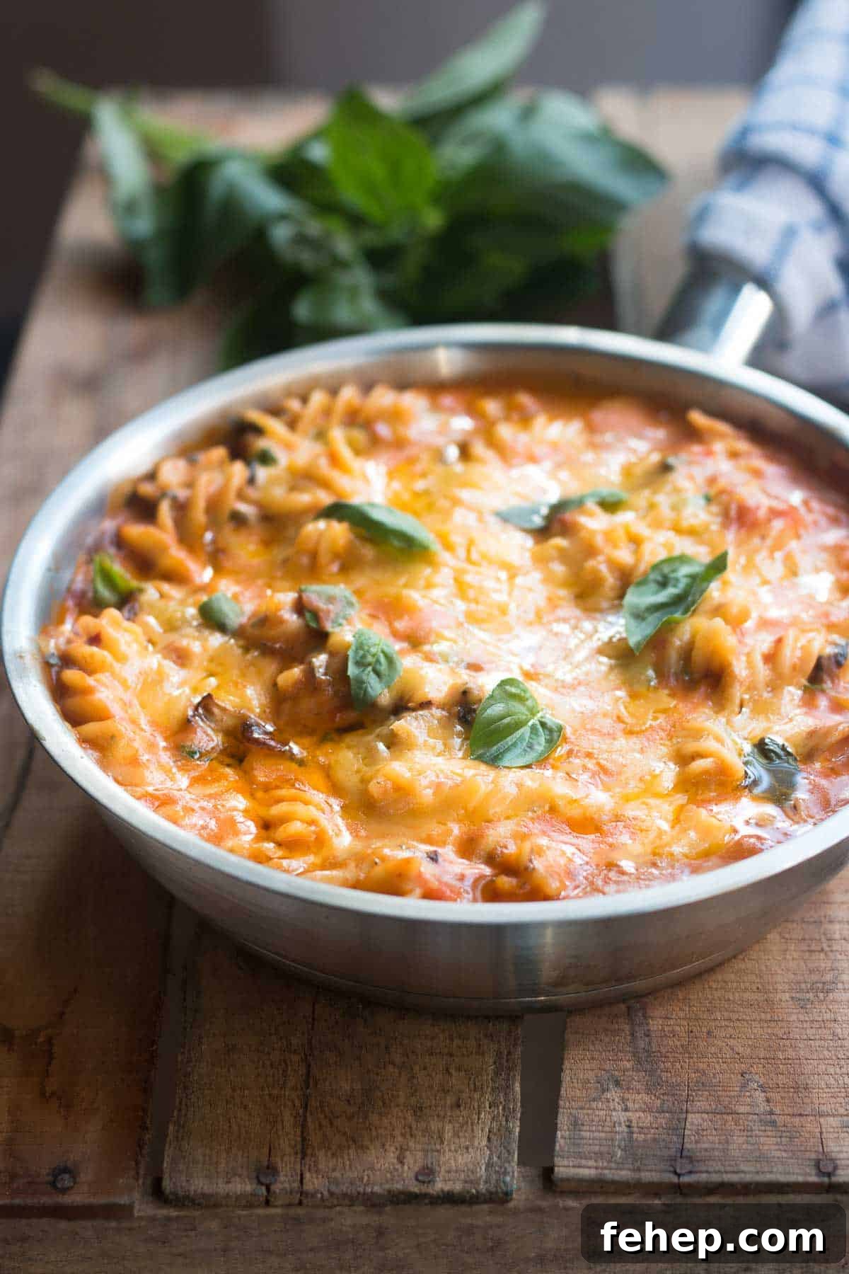 All-In Sunday Veggie Pasta layered with warm, melted cheese and garnished with fresh basil in a skillet.
