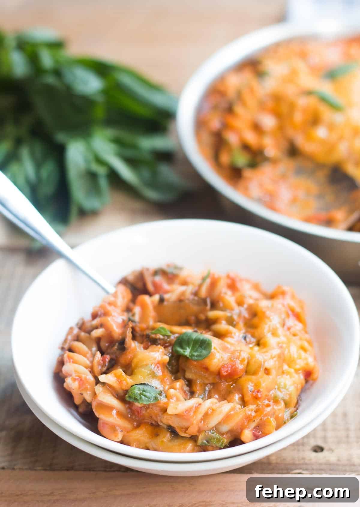 A comforting bowl of cheesy Sunday Veggie Pasta garnished with fresh basil and served in a white bowl.