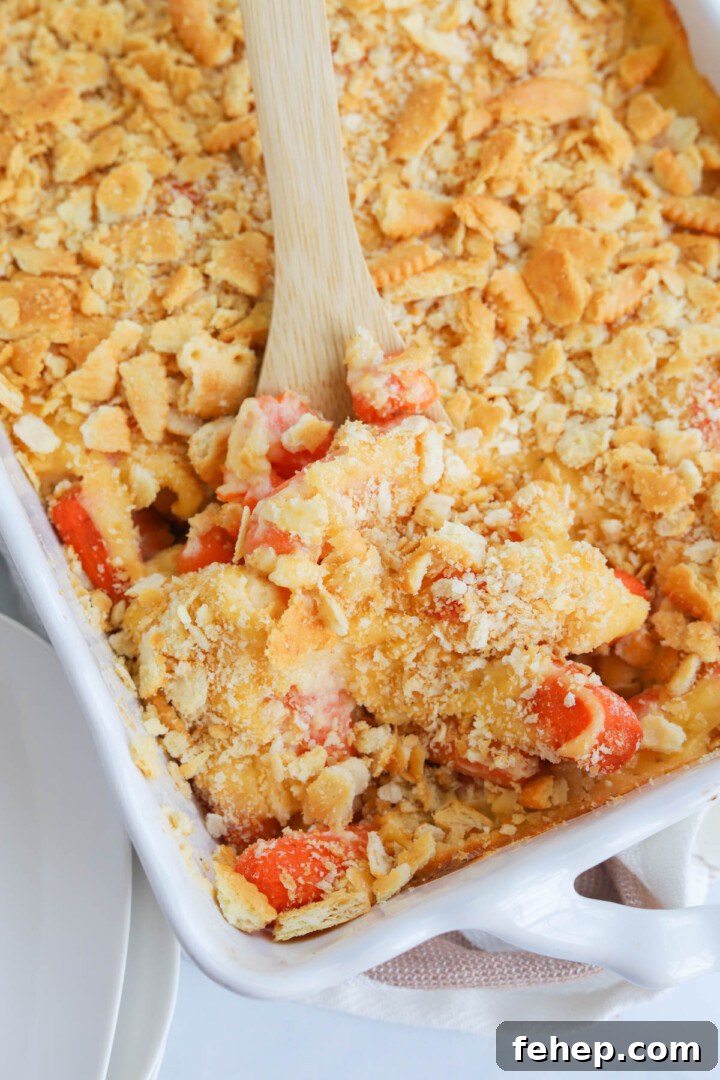 baked carrot casserole being served with wooden spoon.