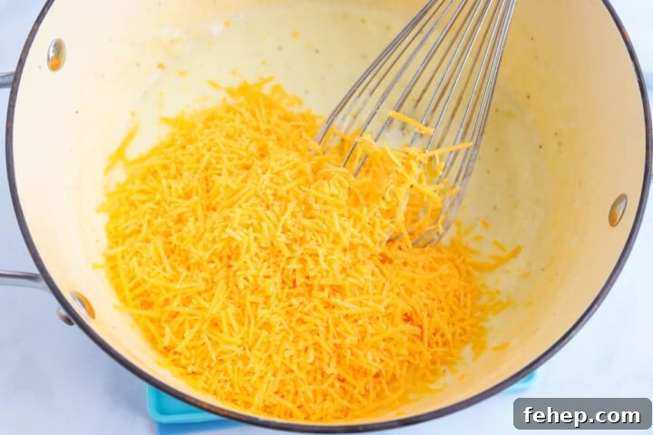 adding cheese to the roux to make the cheese sauce.