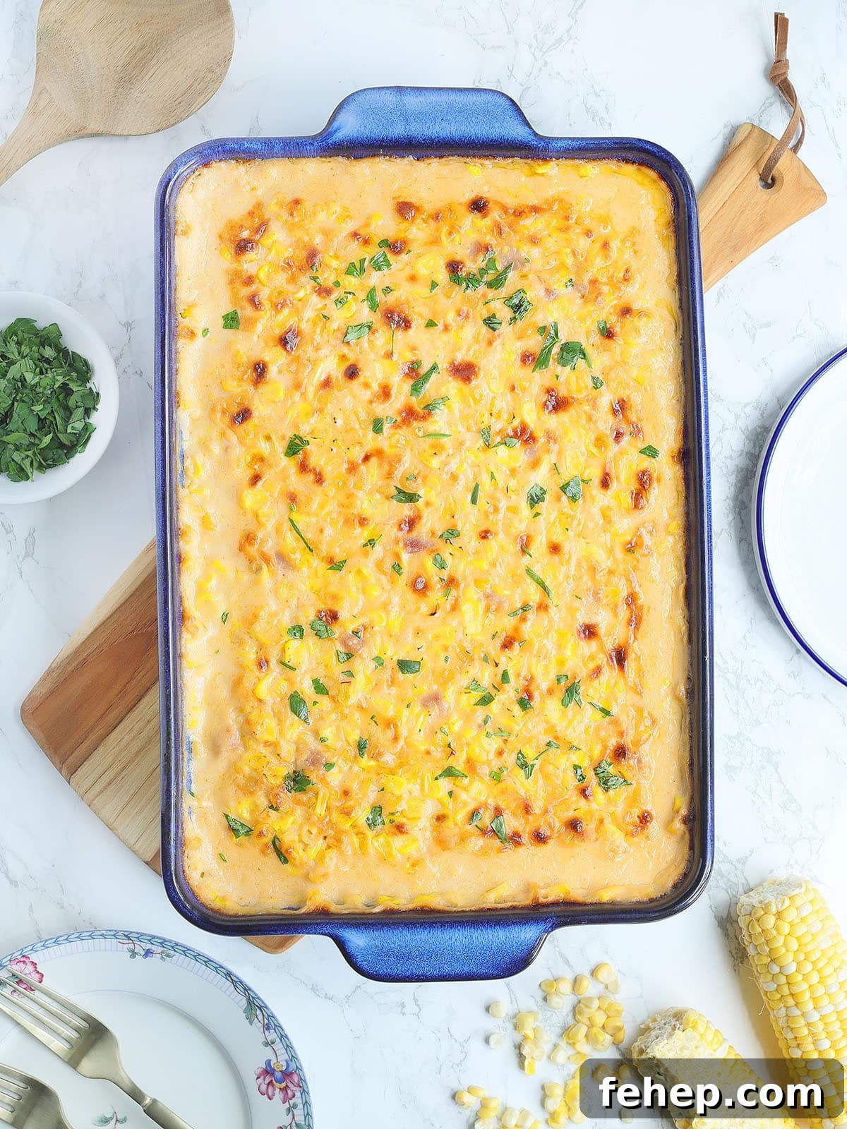 Baked cheesy corn casserole garnished with parsley in a rectangular baking dish.