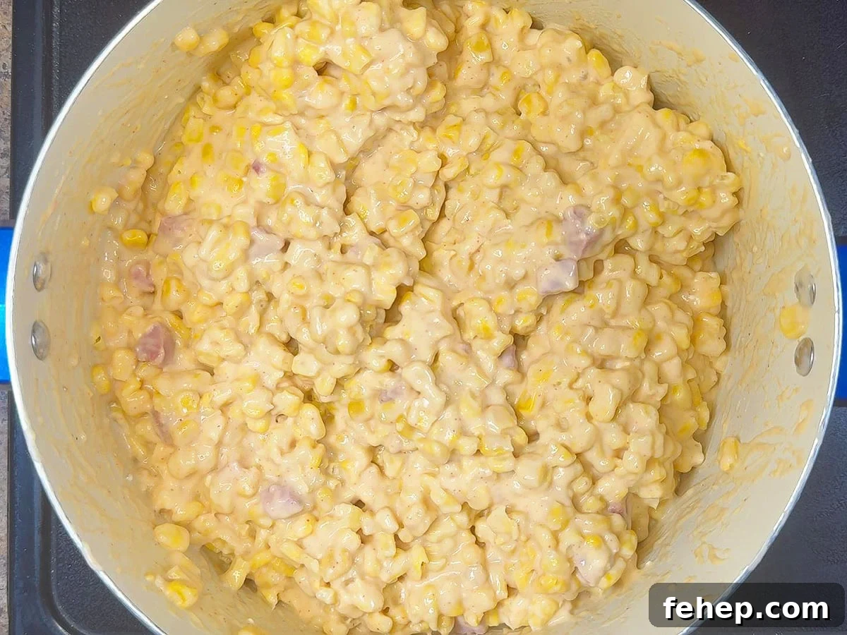 Whole kernel corn added to the pot and coated with the ham and cheese sauce.